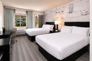 Une chambre d’hôtel avec deux lits, un bureau et une vue sur l’extérieur.