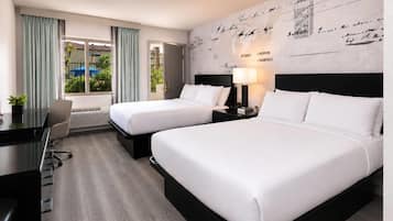 A hotel room with two beds, a desk, and a view of the outdoors.