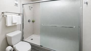 Un baño con ducha envuelta en vidrio, inodoro y toallero.