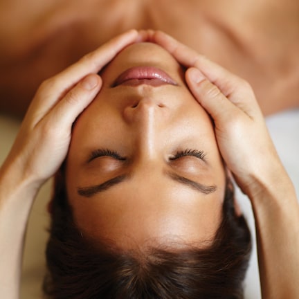 A close-up of a person lying down with hands on their head.