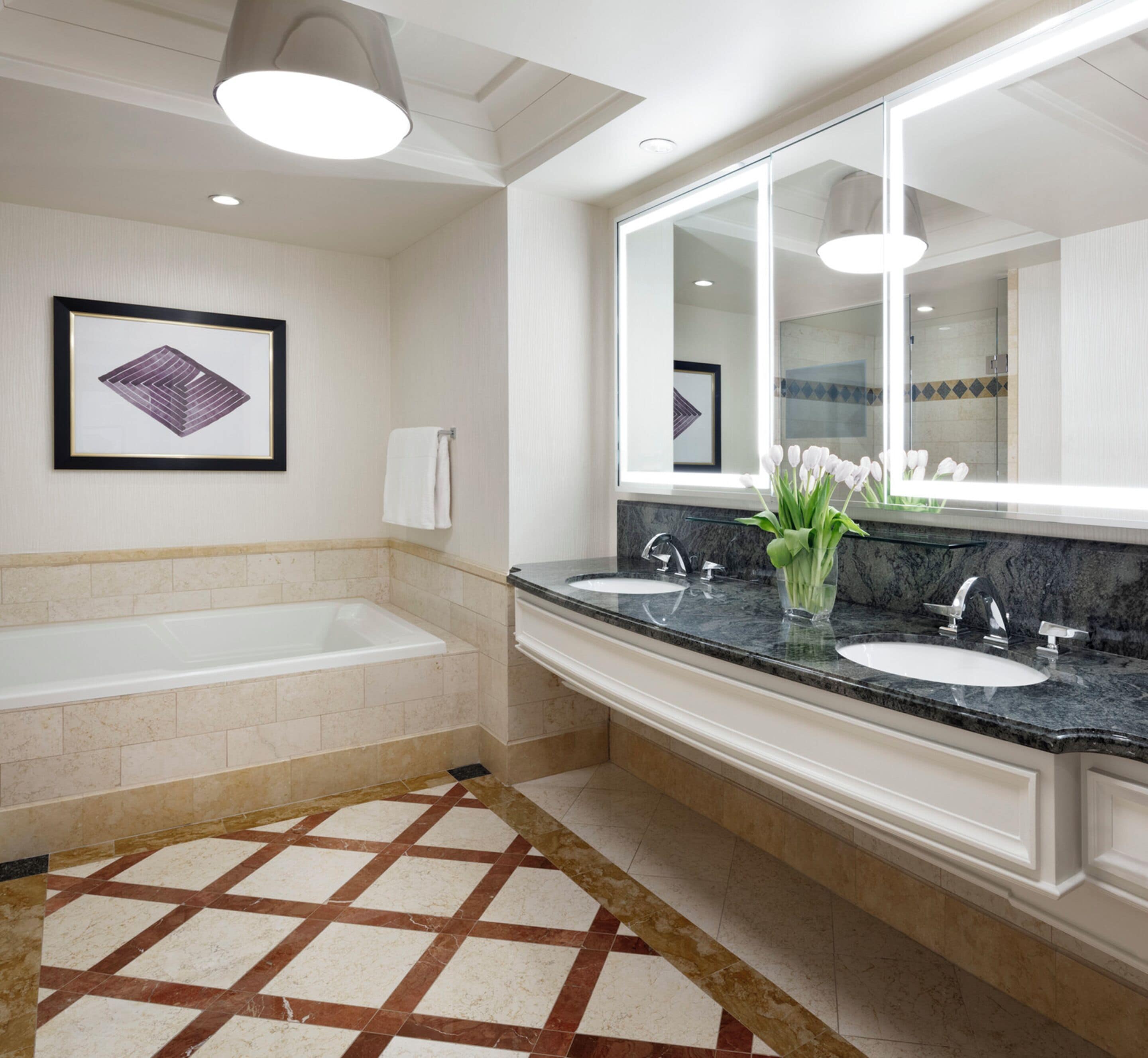 Une salle de bain moderne avec une grande baignoire, deux lavabos, un miroir et une œuvre d’art encadrée accrochée au mur.