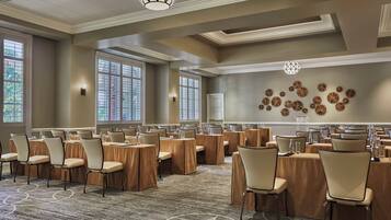 A conference room with multiple tables and chairs, large windows, and decorative wall art.