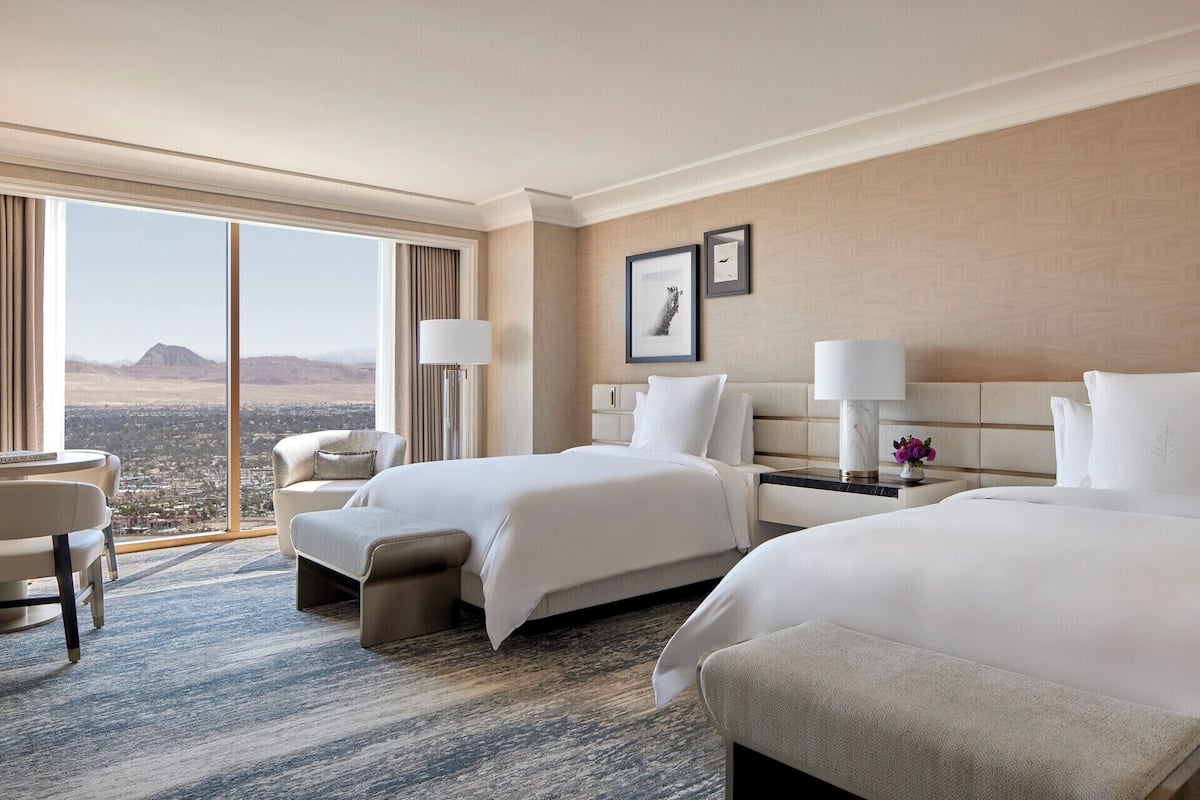 Una habitación de hotel con dos camas, un escritorio y una silla.