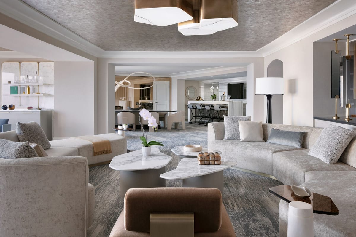 Una sala de estar moderna con un sofá modular, una mesa de centro y un comedor al fondo.