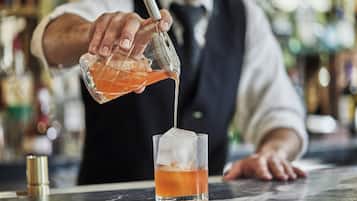 A bartender pouring a drink into a glass with ice.