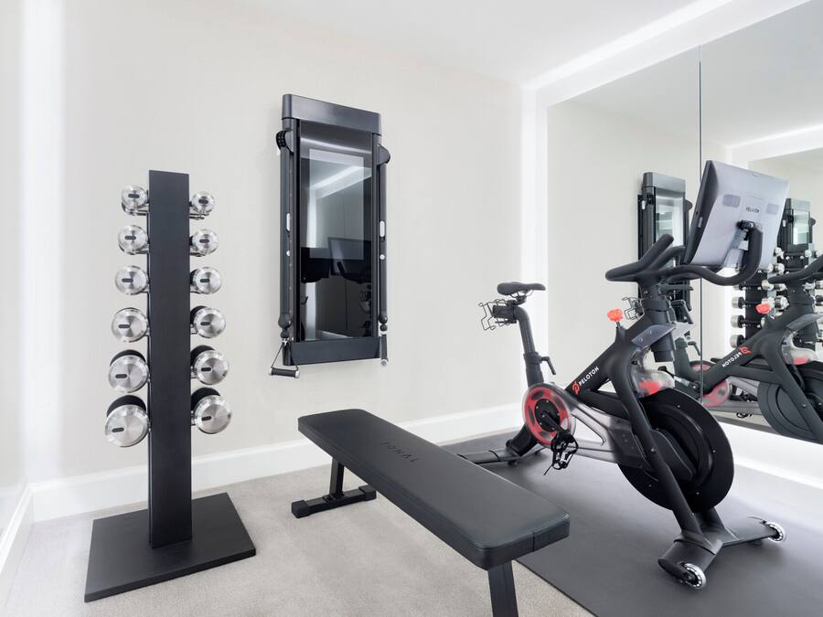A home gym with a stationary bike, weight bench, and a wall-mounted dumbbell rack.