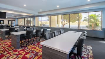 A conference room with a long table, chairs, and large windows with a view of the beach.