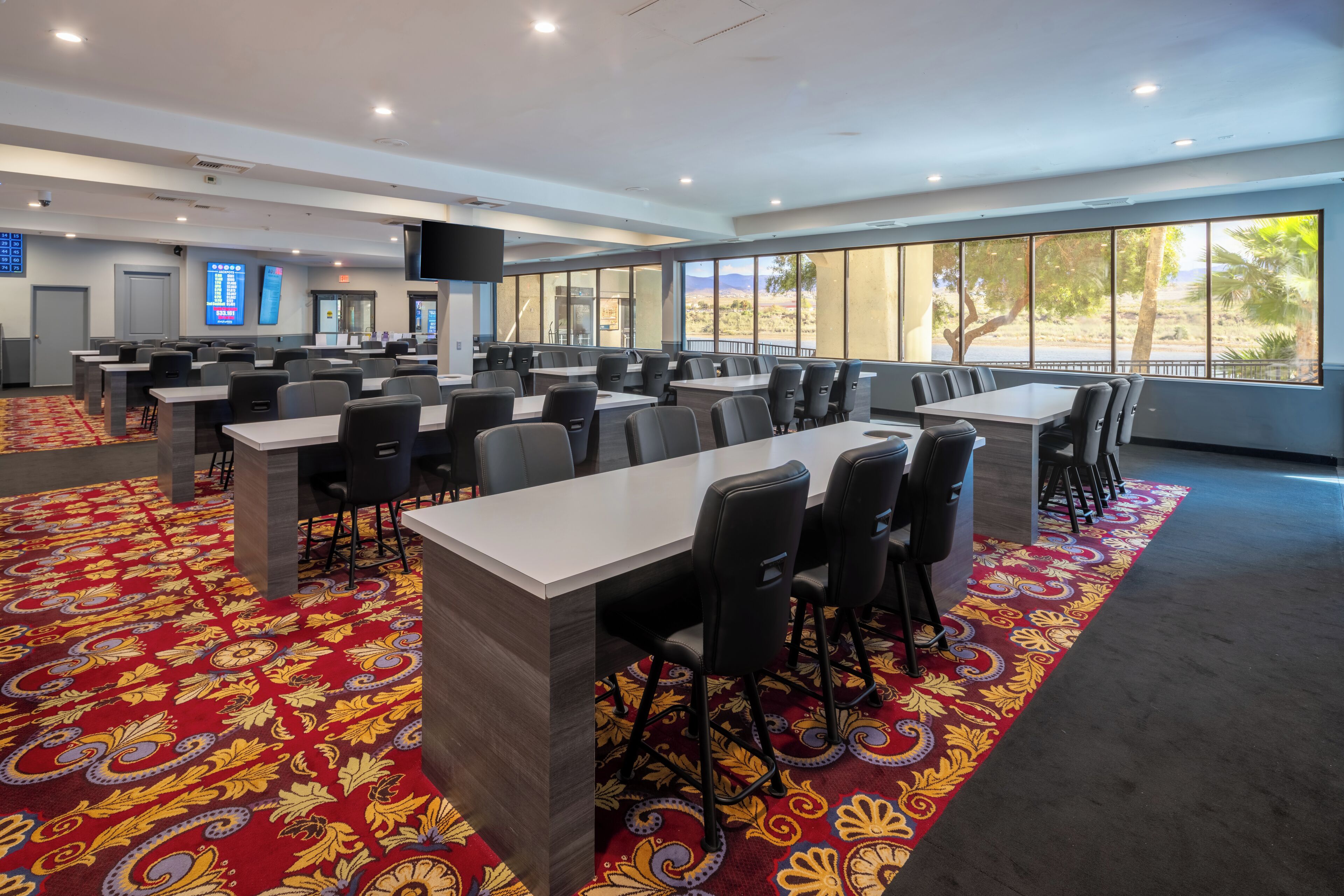 A conference room with tables and chairs, large windows, and a patterned carpet.