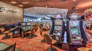 Un casino avec des machines à sous, des tables de jeu et un mur de briques sur lequel est inscrit le nom « Capriotti's ».