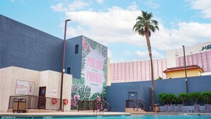 Un espace piscine agrémenté d’une fresque représentant des palmiers et des flamants roses, d’un poste de surveillance pour les sauveteurs et d’un coin salon au bord de la piscine.