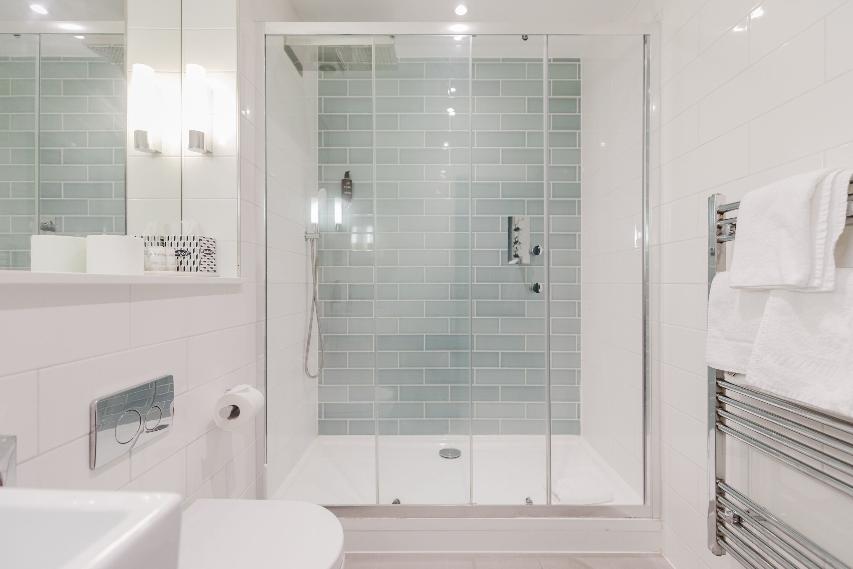 Une salle de bain moderne avec une douche à parois de verre, un lavabo blanc et un porte-serviettes.
