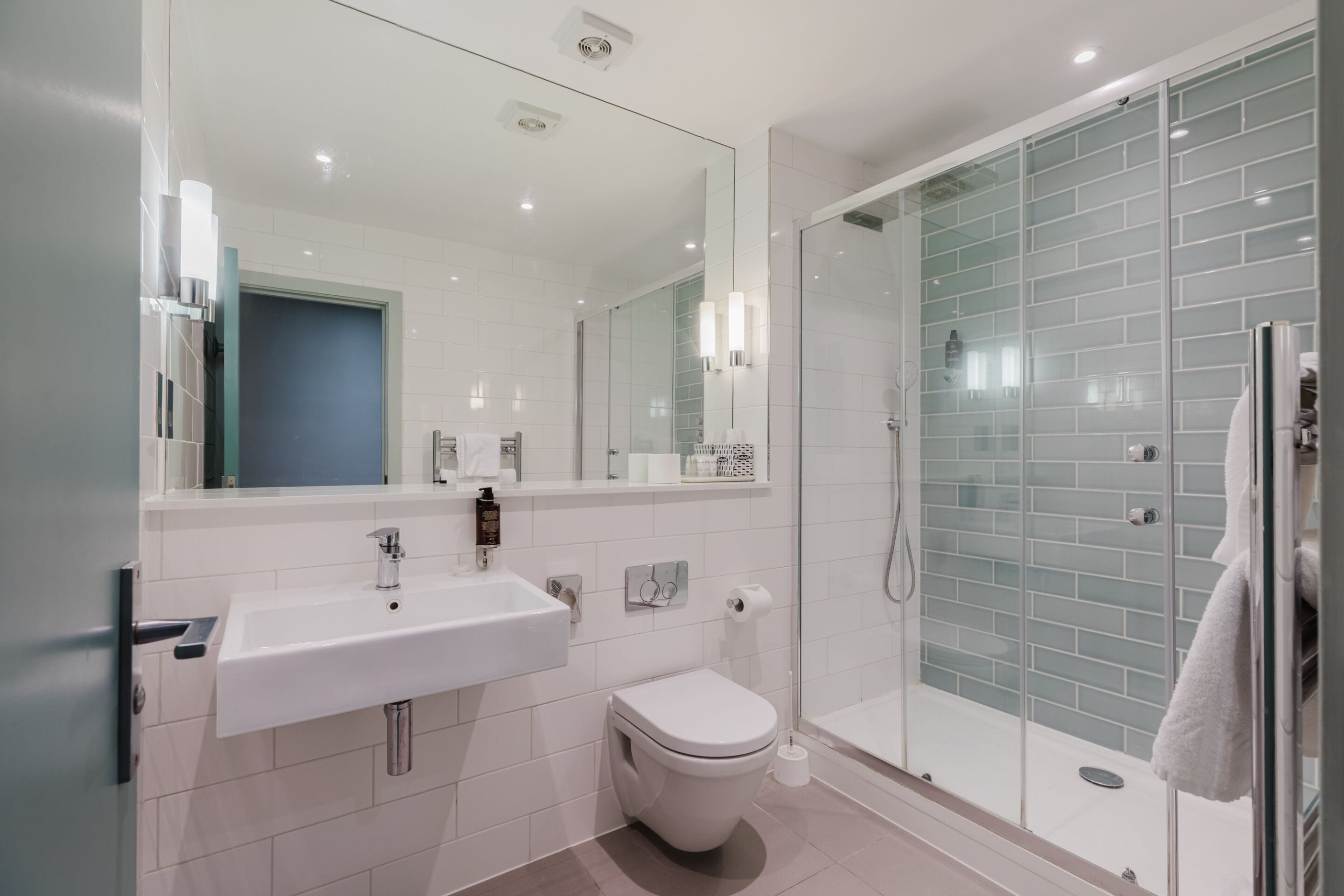 A modern bathroom with a white sink, toilet, and glass shower enclosure.