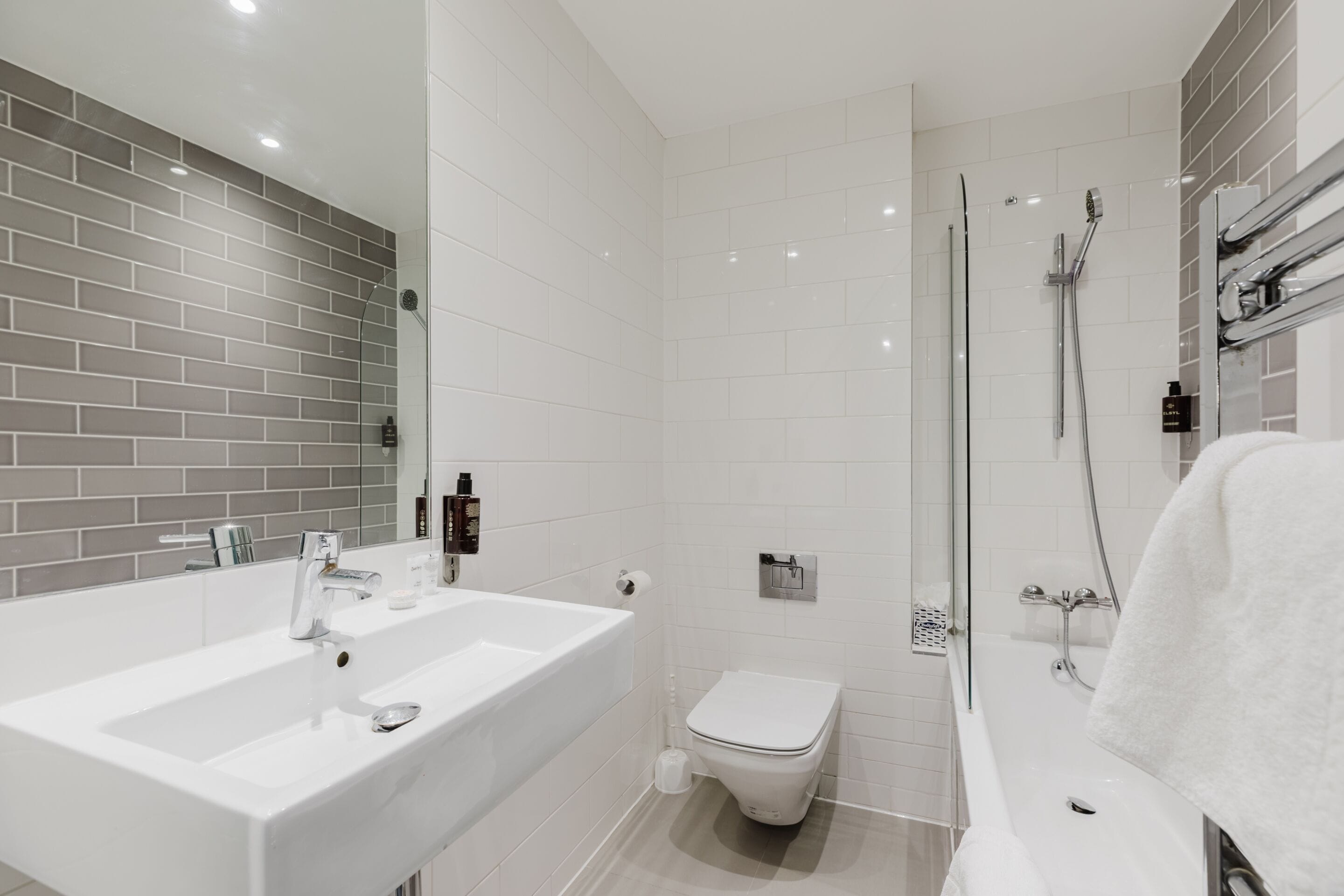 A modern bathroom with a white sink, toilet, and bathtub, and a shower area.