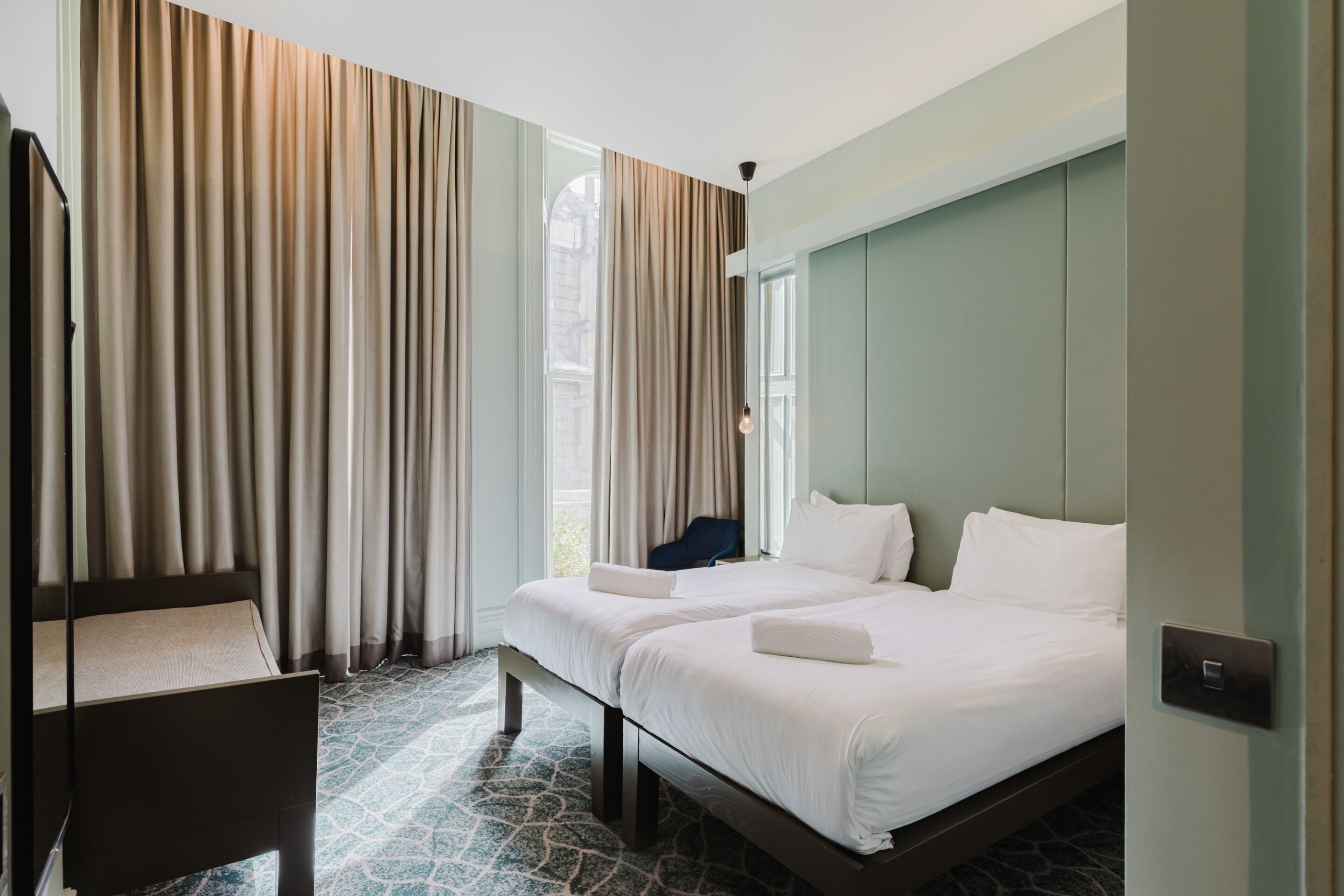 Une chambre d’hôtel avec deux lits, un bureau et une chaise.