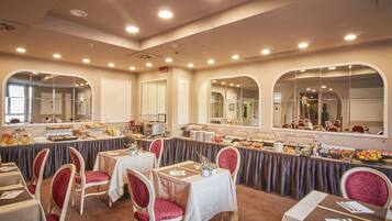 Un salón de banquetes con mesas redondas, sillas y una zona de bufé.