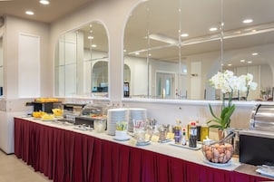 A buffet setup with various food items and condiments, a grill, and a potted plant.