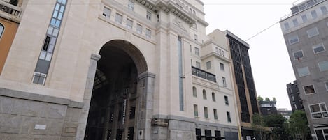 Un edificio histórico con una gran entrada en arco, múltiples ventanas y un letrero que dice 'Hotel Ambassadeur'.