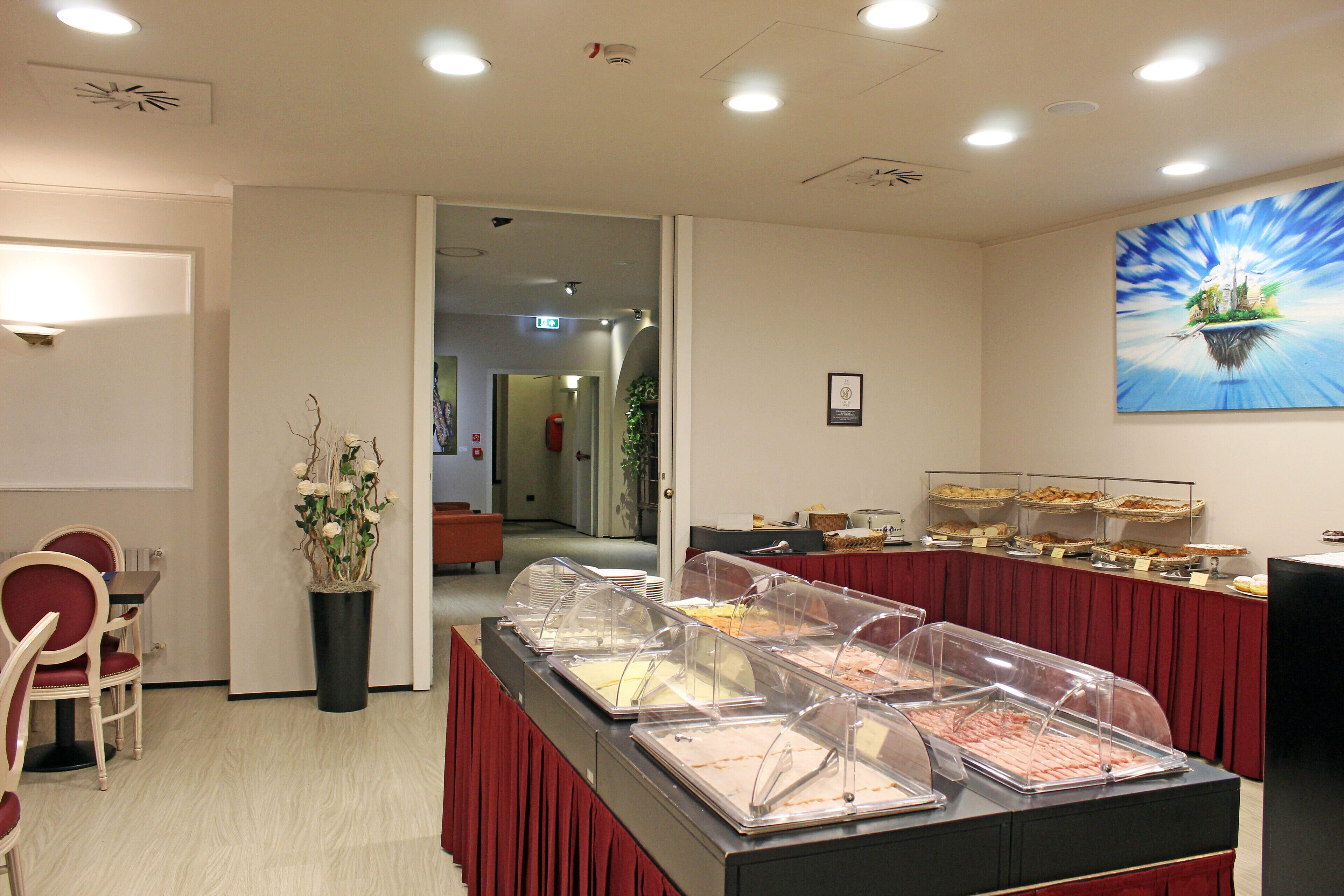 A buffet area with multiple food stations, a potted plant, and a painting on the wall.
