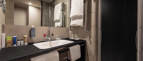 Une salle de bain moderne avec un plan de toilette noir, un lavabo blanc et une cabine de douche en verre.