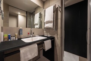 Een moderne badkamer met een zwart aanrecht, een witte wastafel en een douchecabine van glas.