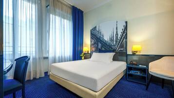 Ein Hotelzimmer mit einem großen Bett, einem Schreibtisch, einem Stuhl und einem Stadtbild an der Wand.
