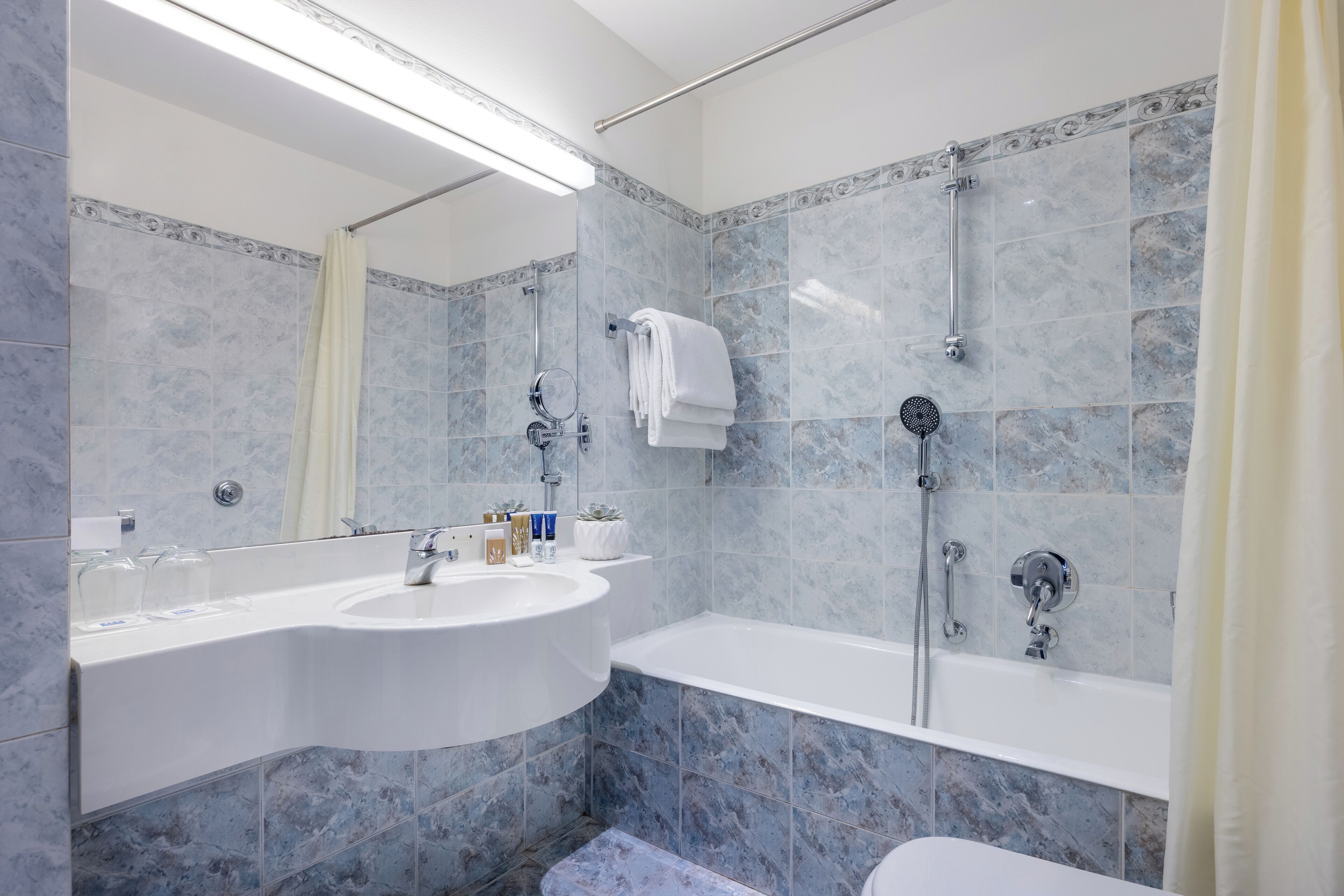 A modern bathroom with a curved sink, a bathtub, and a shower.