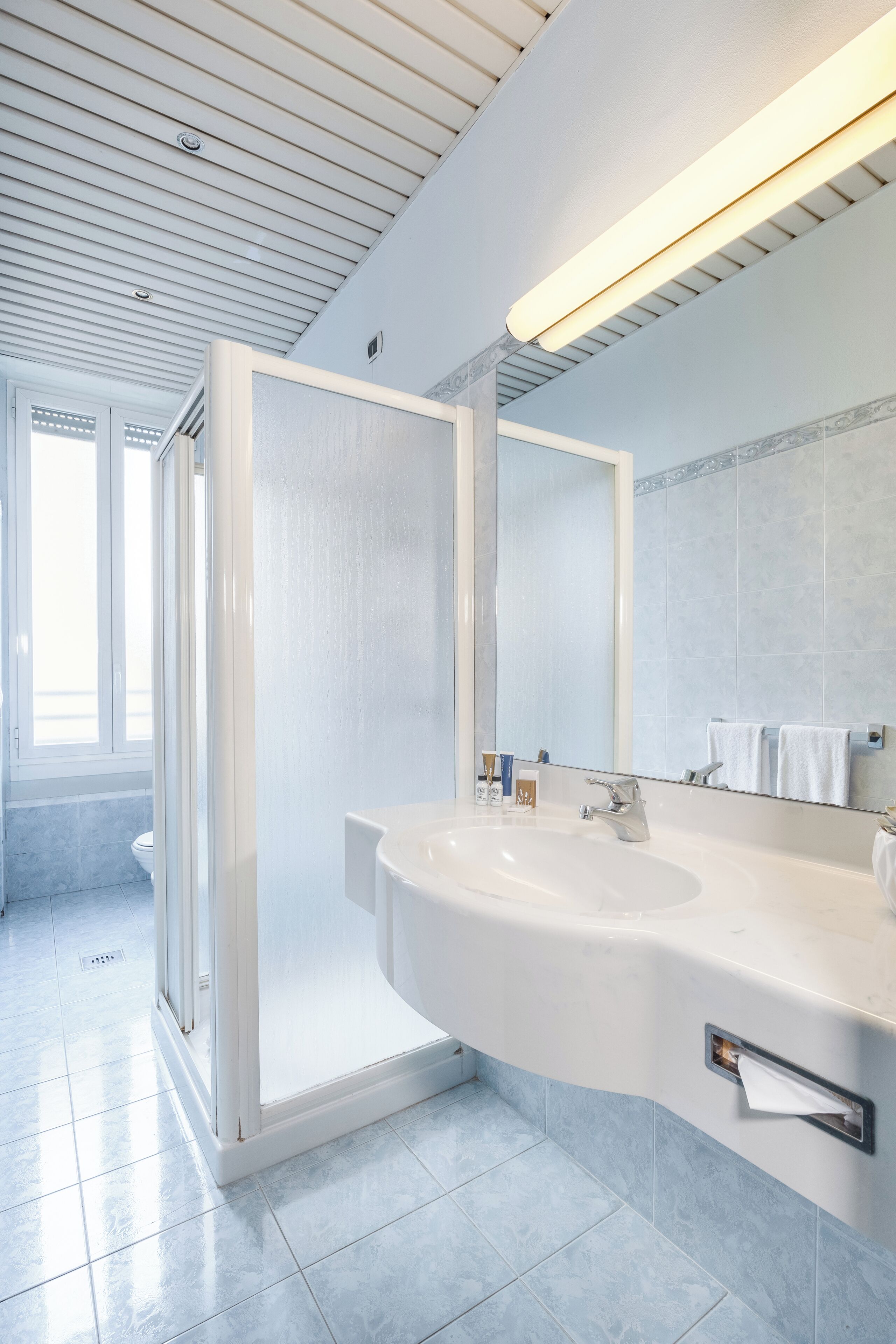 A modern bathroom with a large sink, mirror, and shower enclosure.