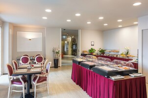 Una sala conferenze con un lungo tavolo, sedie e un'area buffet con presentazioni di cibi.