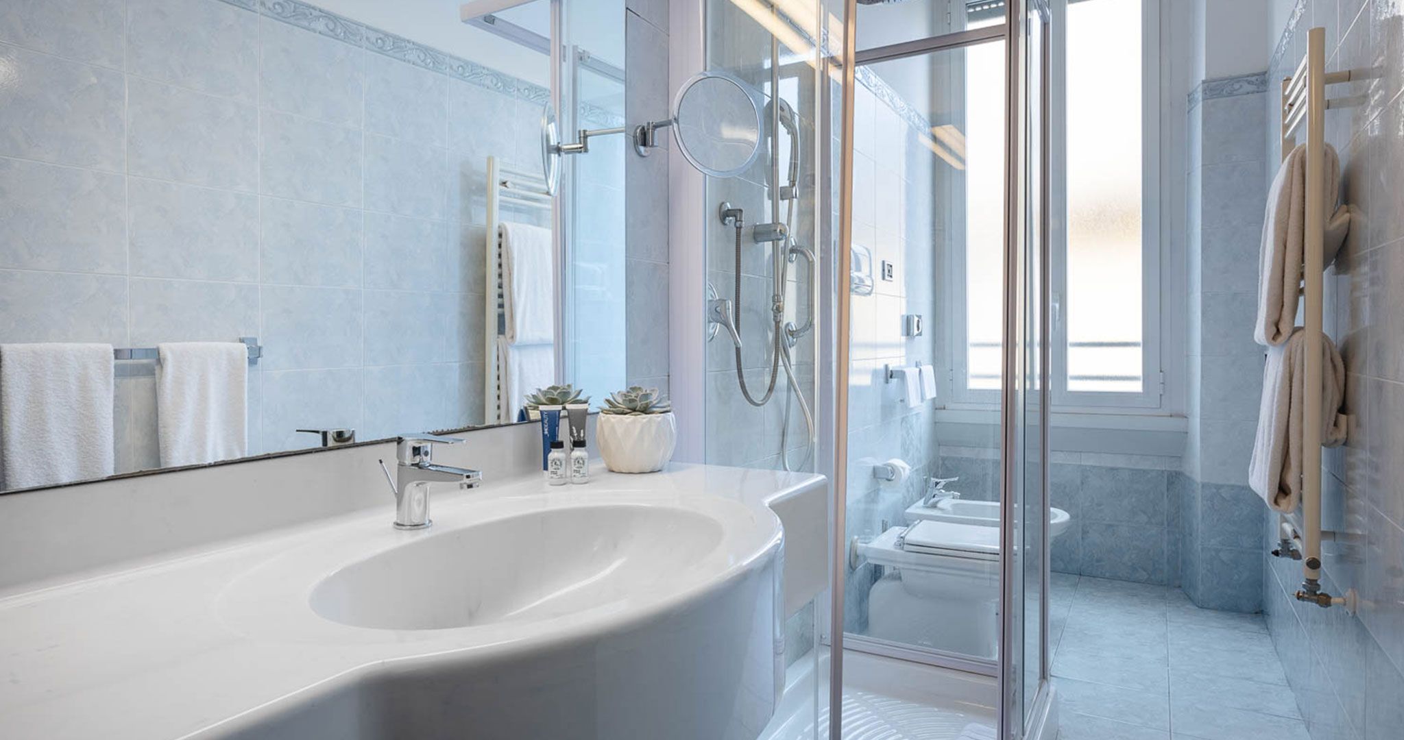 Un baño moderno con un lavamanos grande de color blanco, una cabina de ducha de vidrio y un inodoro a la vista.