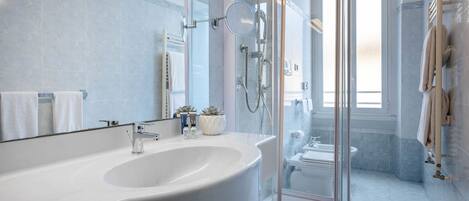Un baño moderno con un lavamanos grande de color blanco, una cabina de ducha de vidrio y un inodoro a la vista.
