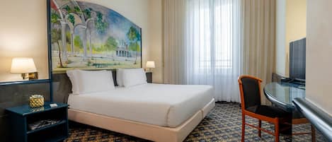 Habitación de hotel con una cama, dos mesitas de noche, un escritorio con silla, un cuadro en la pared y un gran ventanal con cortinas.
