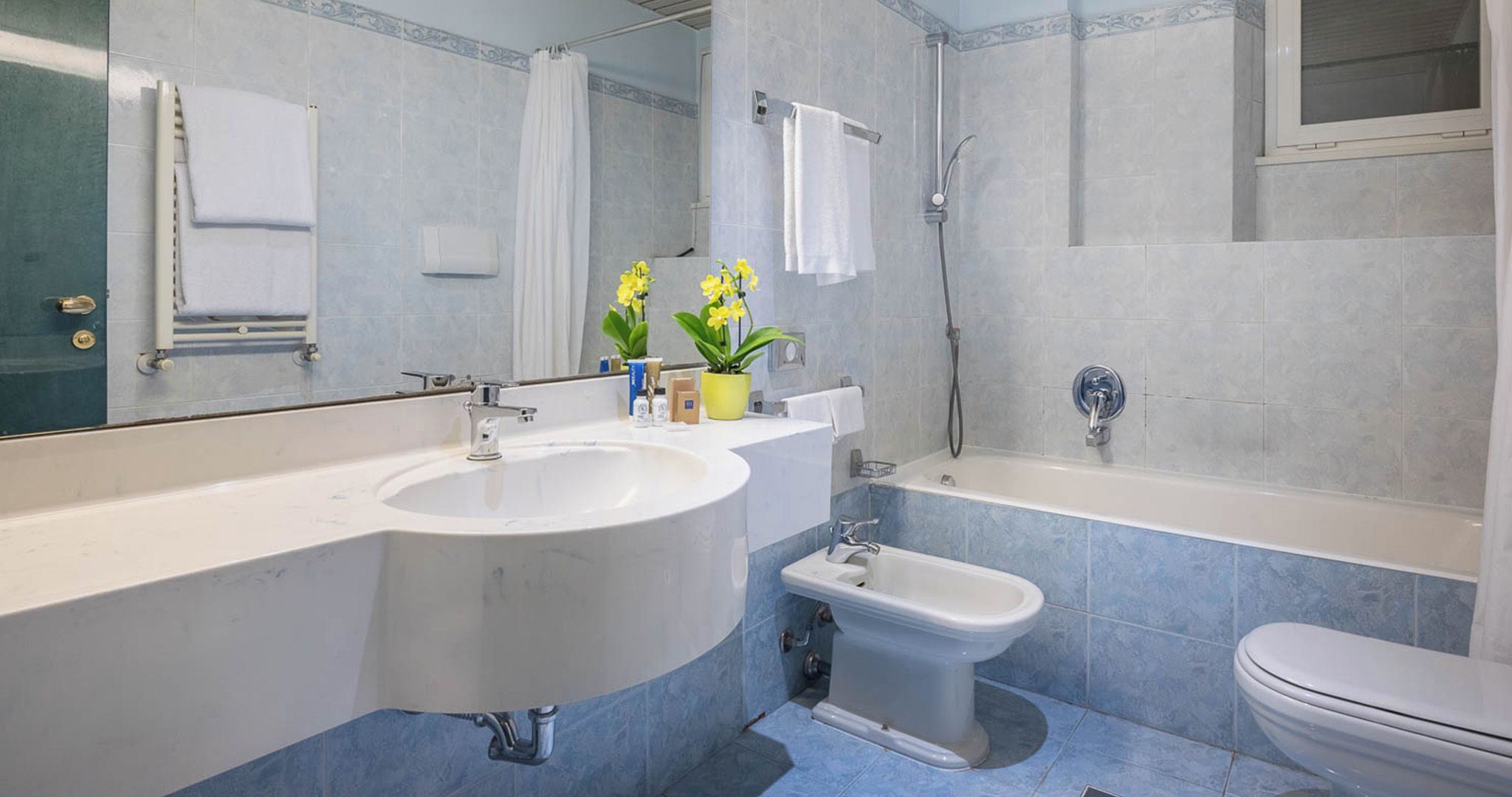 A bathroom with a sink, bidet, toilet, and shower.