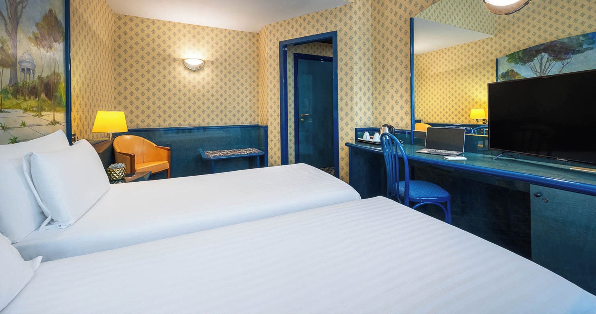 A hotel room with a bed, desk, chair, and a television.