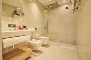 Et moderne badeværelse med et glasvægshus, et trækommode, et toiletbidé og et toilet.