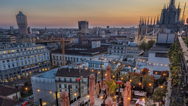 A rooftop terrace with tables and chairs, surrounded by city views and a distinctive building with a spire. - iH Hotels Milano Ambasciatori (Milan)