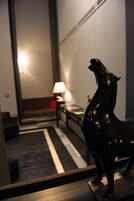 A room with a sofa, a lamp, and a statue of a horse.