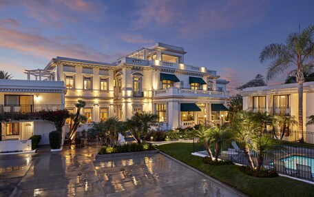 A large, elegant hotel with a spacious courtyard, a swimming pool, and lush landscaping.