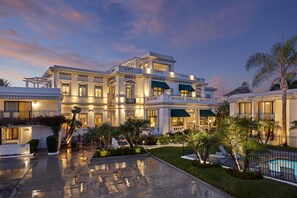 A large, elegant hotel with a spacious courtyard, a swimming pool, and lush landscaping.