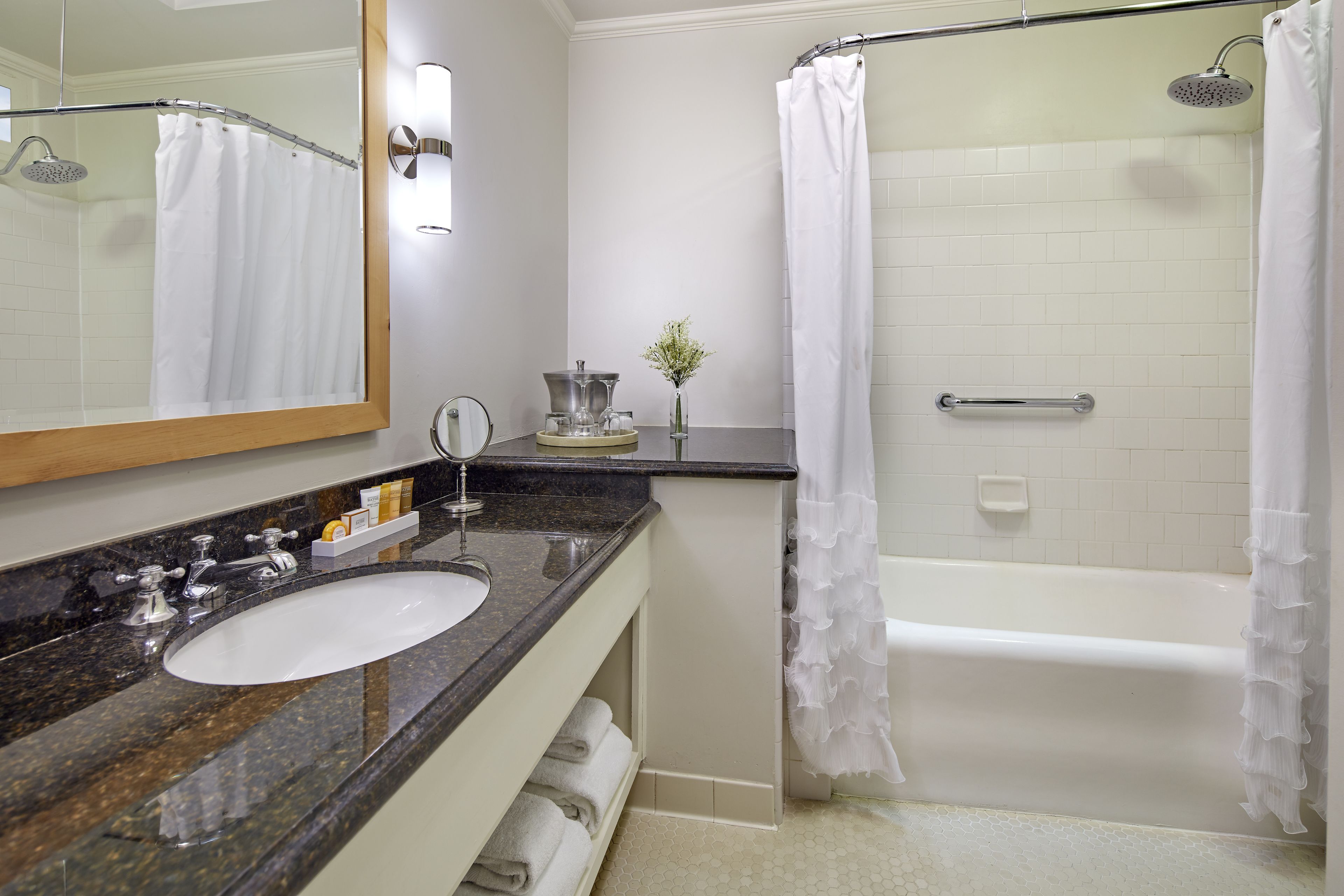 A bathroom with a sink, mirror, shower, and bathtub.