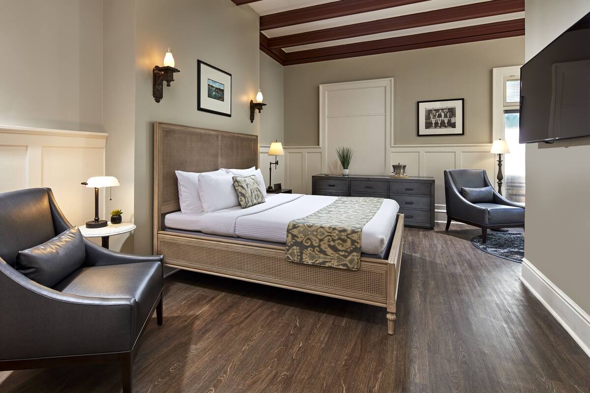 A bedroom with a bed, a chair, a dresser, and a television.