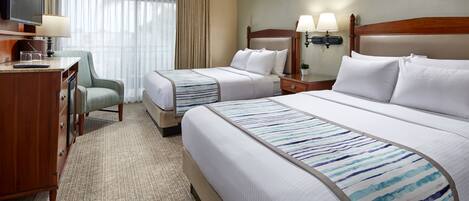Une chambre d’hôtel avec deux lits, un bureau, une chaise et un téléviseur.