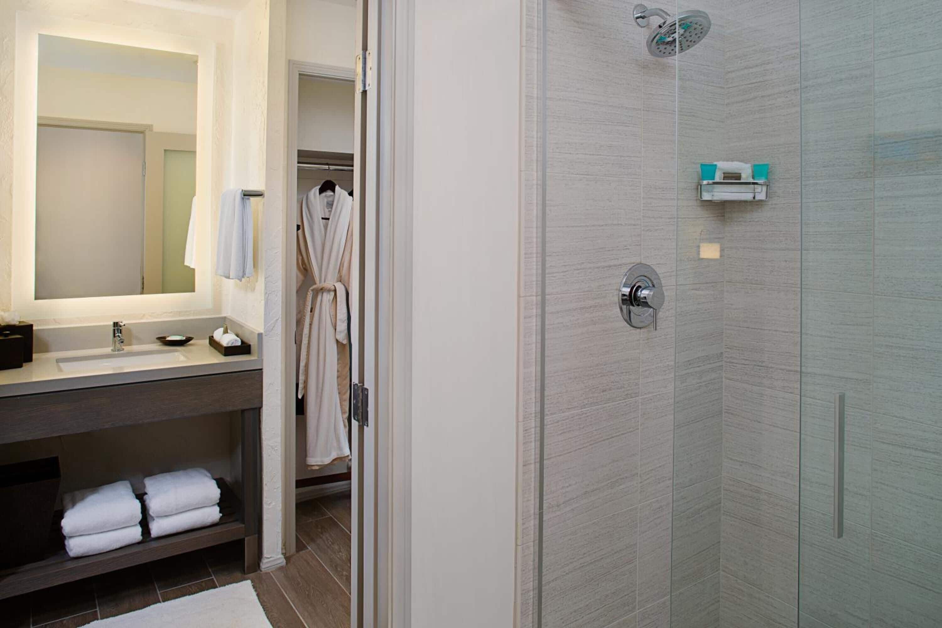A modern bathroom with a glass shower enclosure, a vanity with a mirror, and a towel rack.