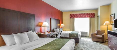 A hotel room with two beds, a desk, a chair, a television, and a window with curtains.