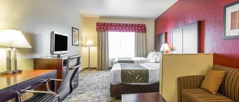 Habitación de hotel con escritorio, silla, televisor, cama y sofá.