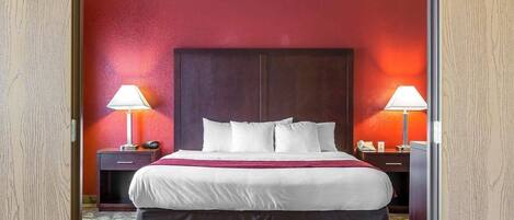 Una habitación de hotel con una cama grande, dos mesitas de noche y una pared de acento roja.