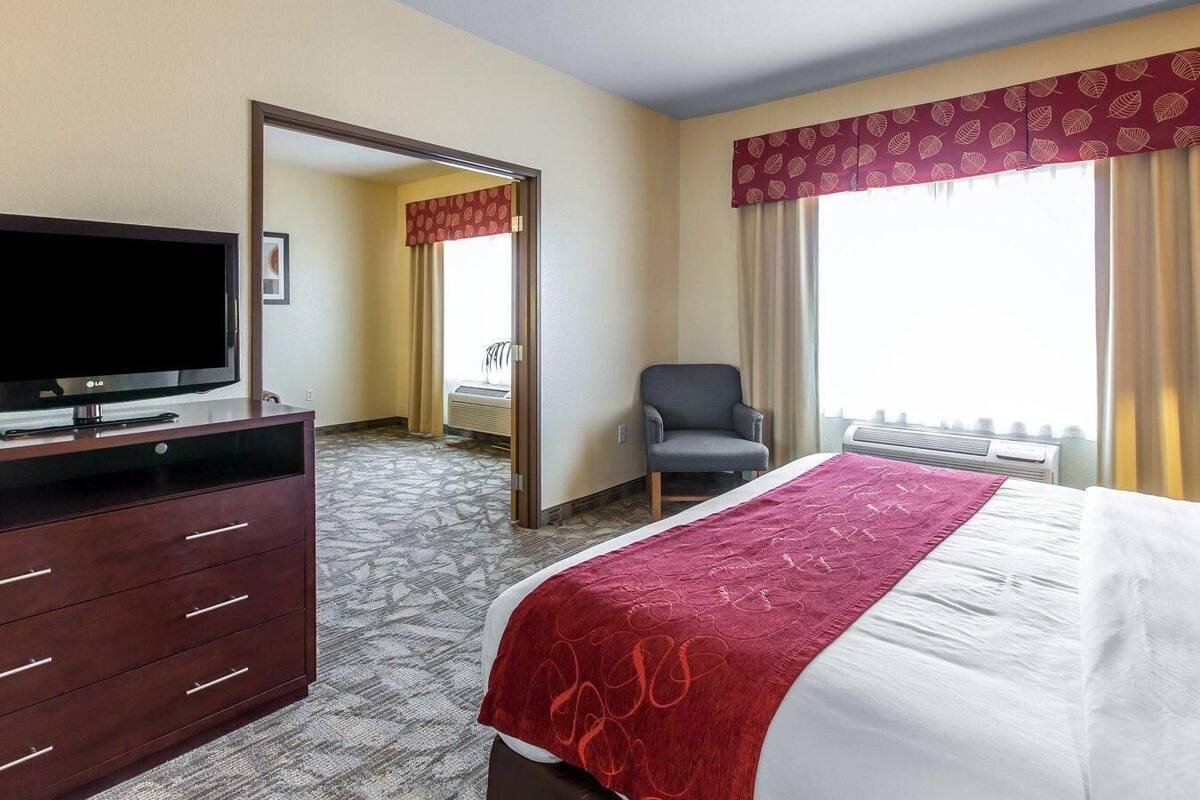 Een hotelkamer met een bed, een televisie, een stoel, een bureau en een raam met gordijnen.