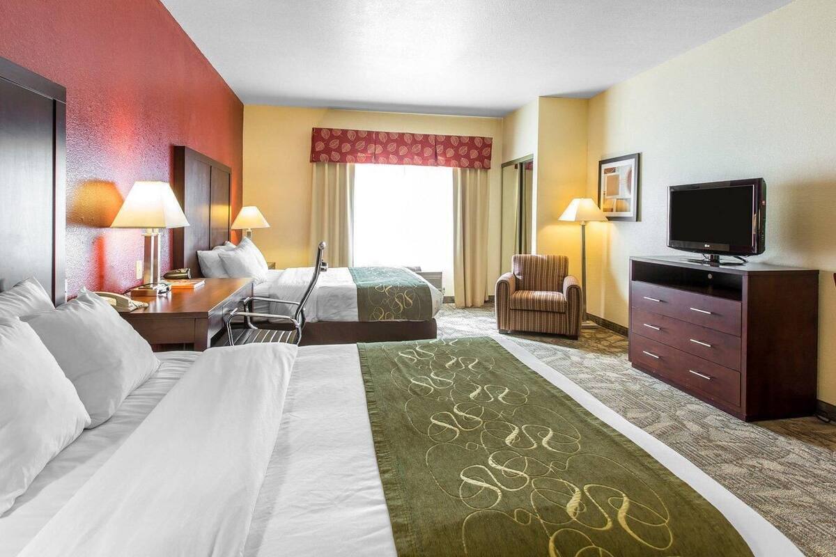 Een hotelkamer met twee bedden, een televisie, een bureau en een stoel.