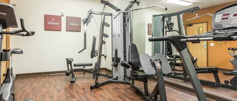 Un gimnasio con equipo de ejercicio, una cinta de correr y letreros motivacionales en la pared.
