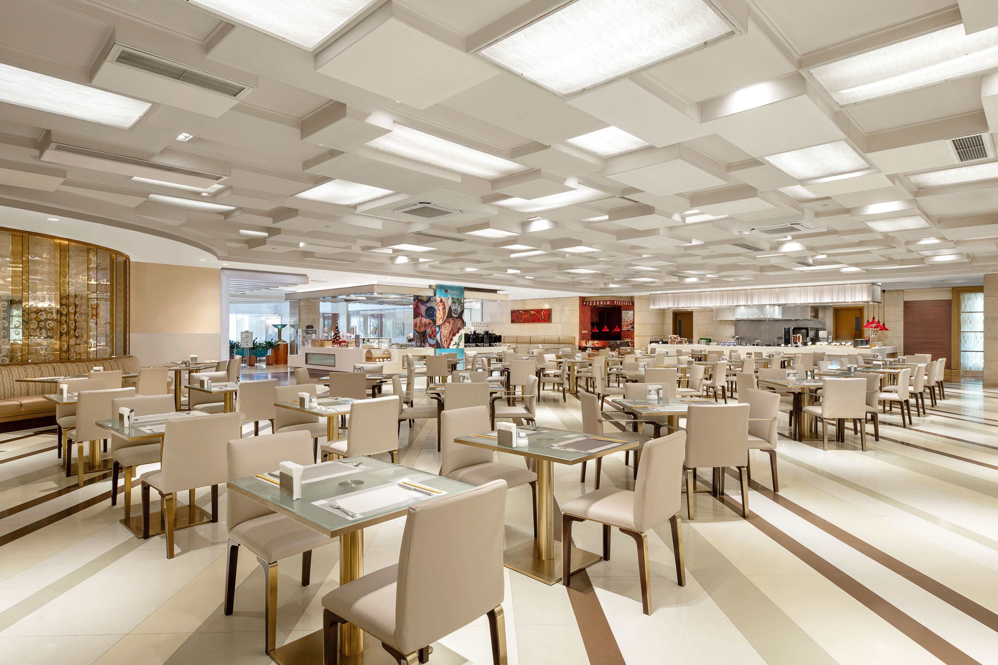 Ruime eetruimte met meerdere tafels en stoelen, een bar in het midden en een modern plafondontwerp.