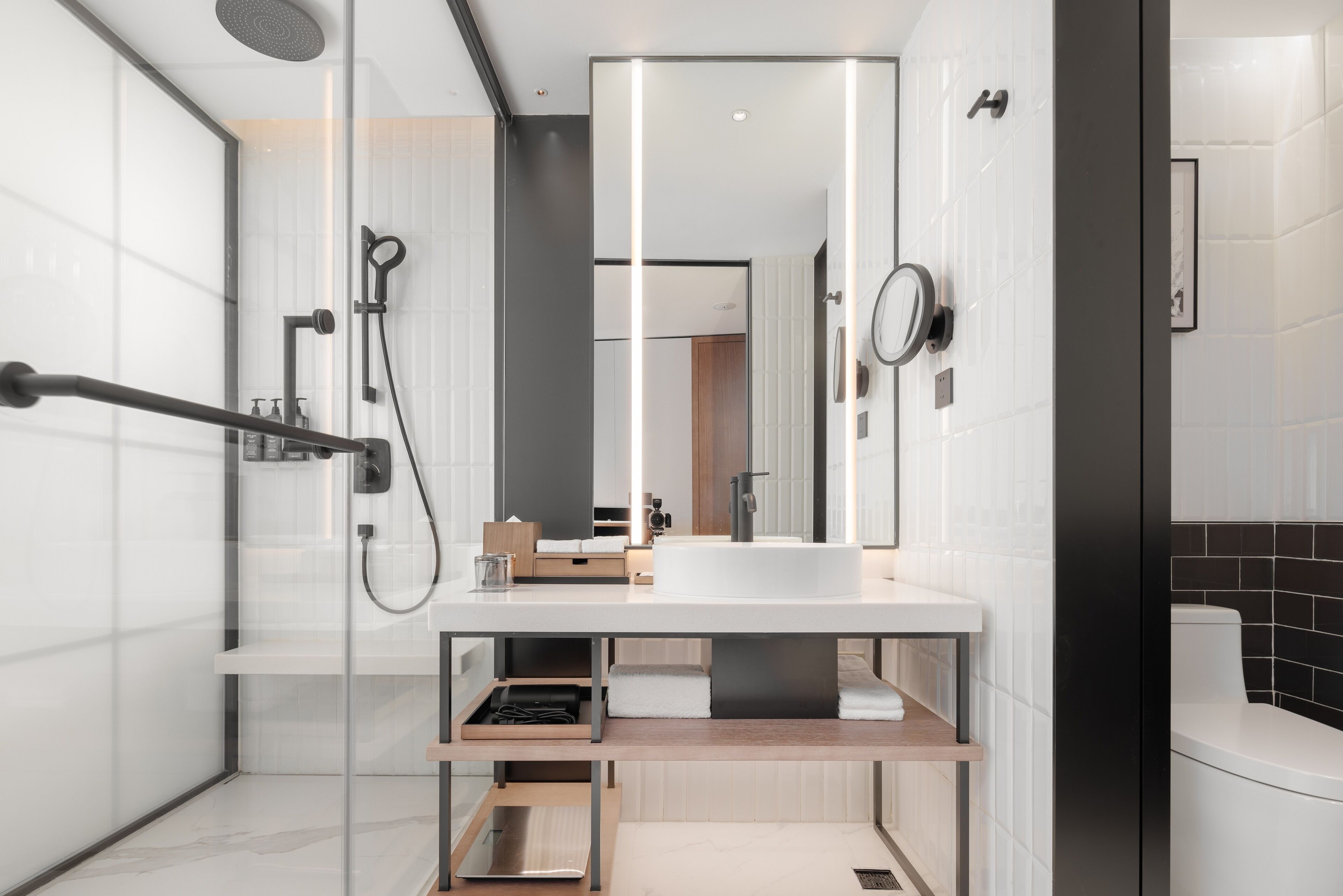 Un baño moderno con cabina de ducha de vidrio, un lavabo blanco y un espejo.